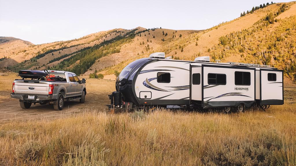 rv and trailer boondocking in grassy field surrounded by mountains in ketchum