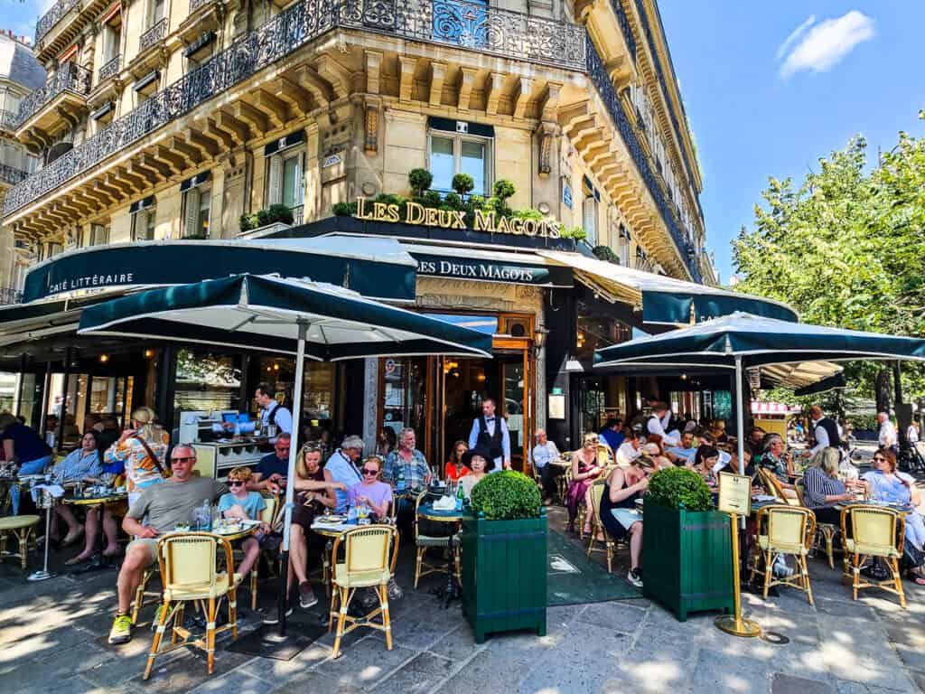 people sitting outside les deux magots in paris