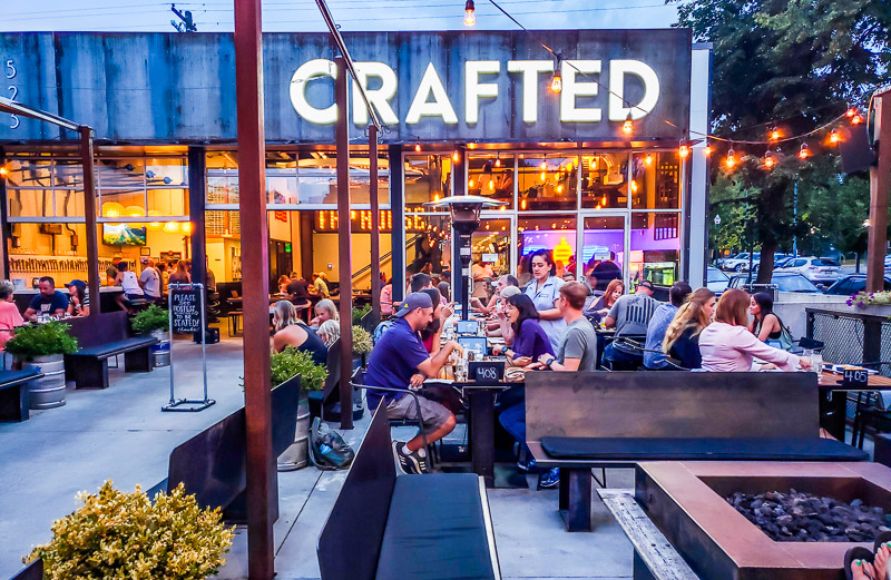 people sitting on patio of crafted brewery and kitchen