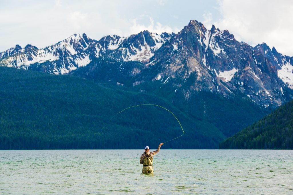 man standing in redfish lake fly fishing