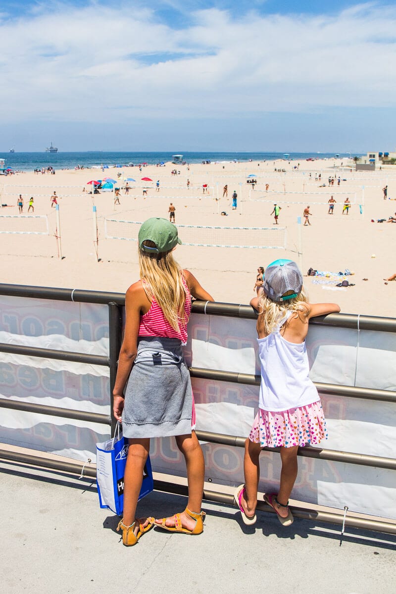 girls looking at Huntington Beach and people playing volleyball