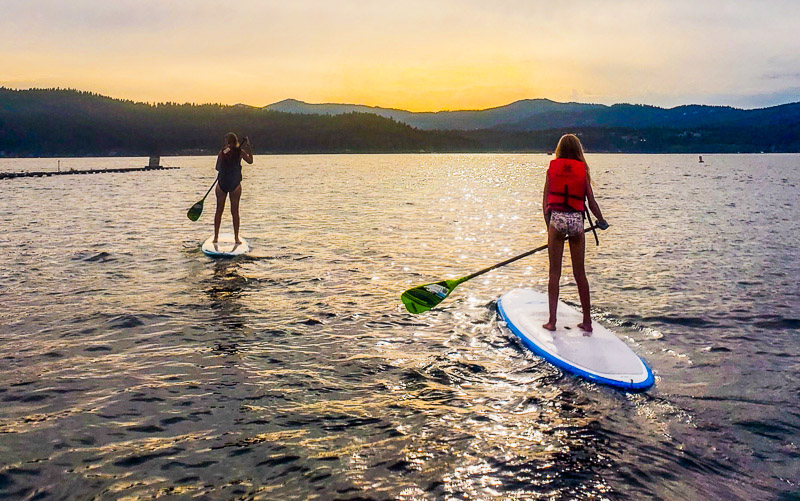 woman and child on stand up paddle boards on lake coer de lane