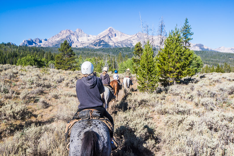 family horseriding with views of sawtooth mountains