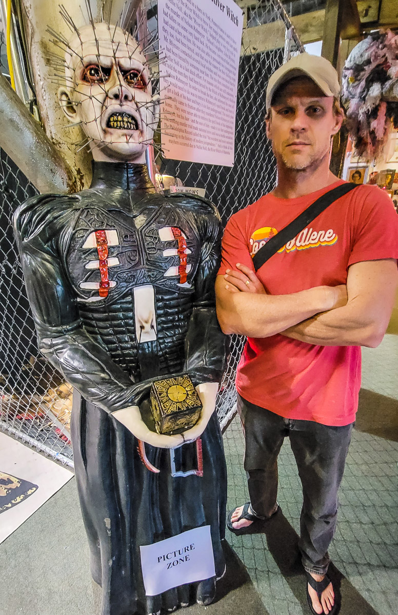 man standing beside wax figure with pins in face