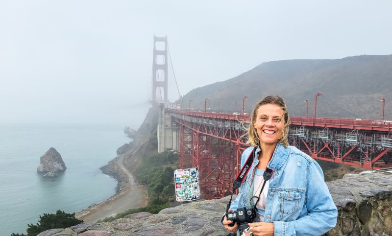 woman posing with camera in front of golden gate bridge view