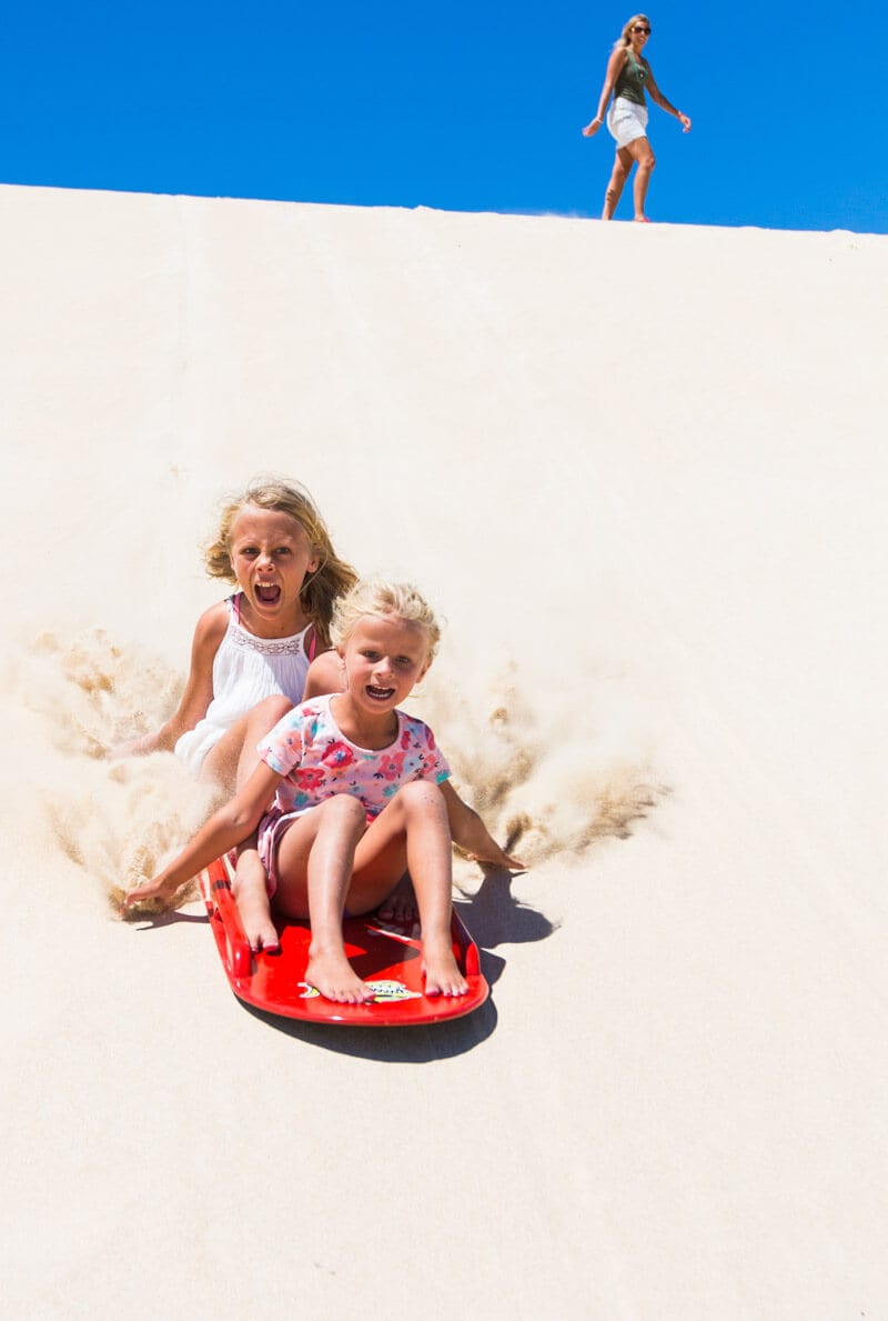 girls Sandboarding the Little Sahara sand dunes 