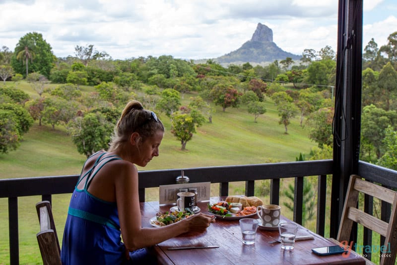 woman eating breakfast at the Lookout Cafe with views of the Glass House Mountains 