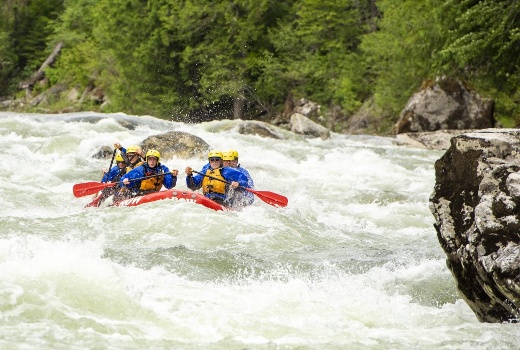 group of people on raft in wild white water in idaho