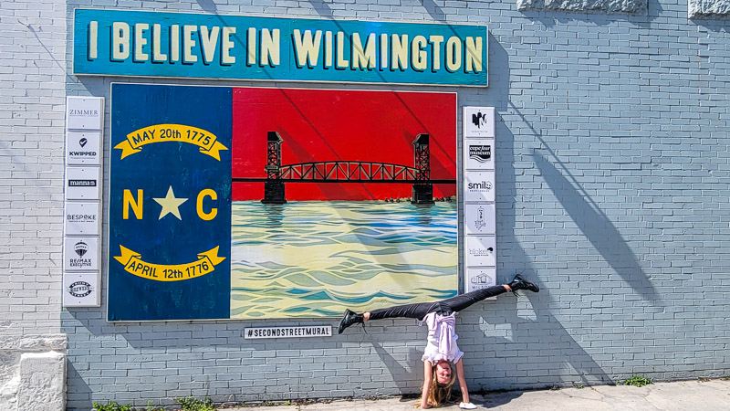 girl doing a handstand against a brick wall