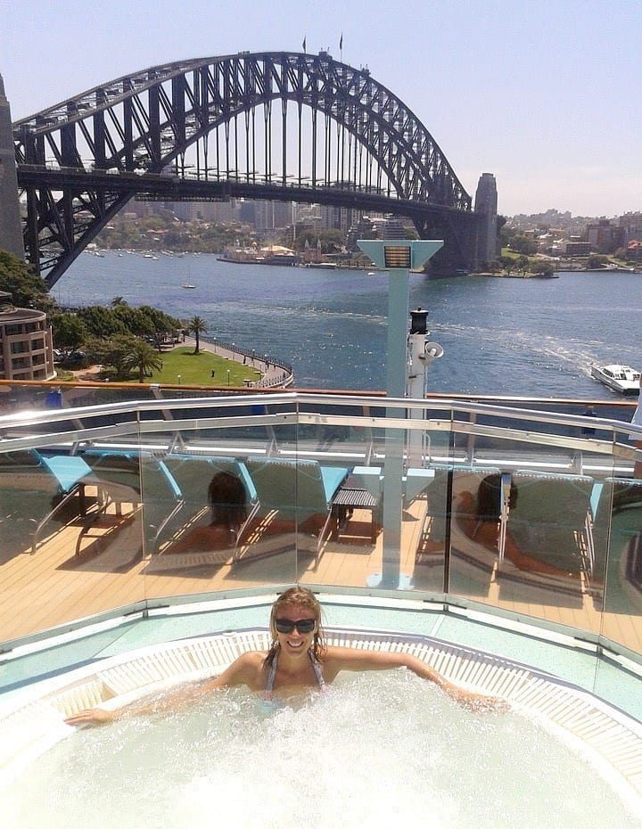 woman in hot tub on carnival spirit with Sydney harbor bridge behind her