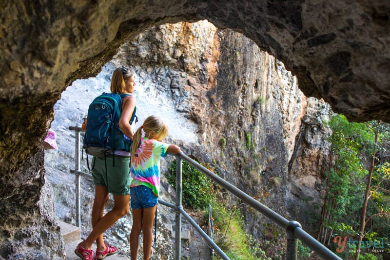 woman and child looking at view out of cave on the Caves Walk at Binna Burra Lodge, Gold Coast Hinterland, Queensland, Australia