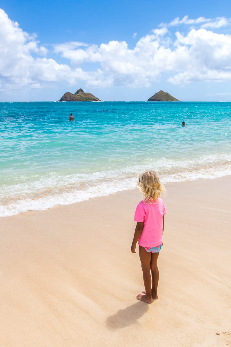 young girl standing on Lanikai Beach looking at water and island