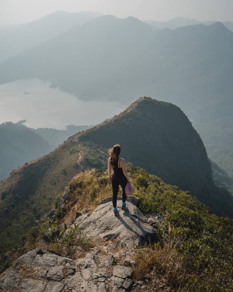 girl looking at view over water from narrow mountain peak