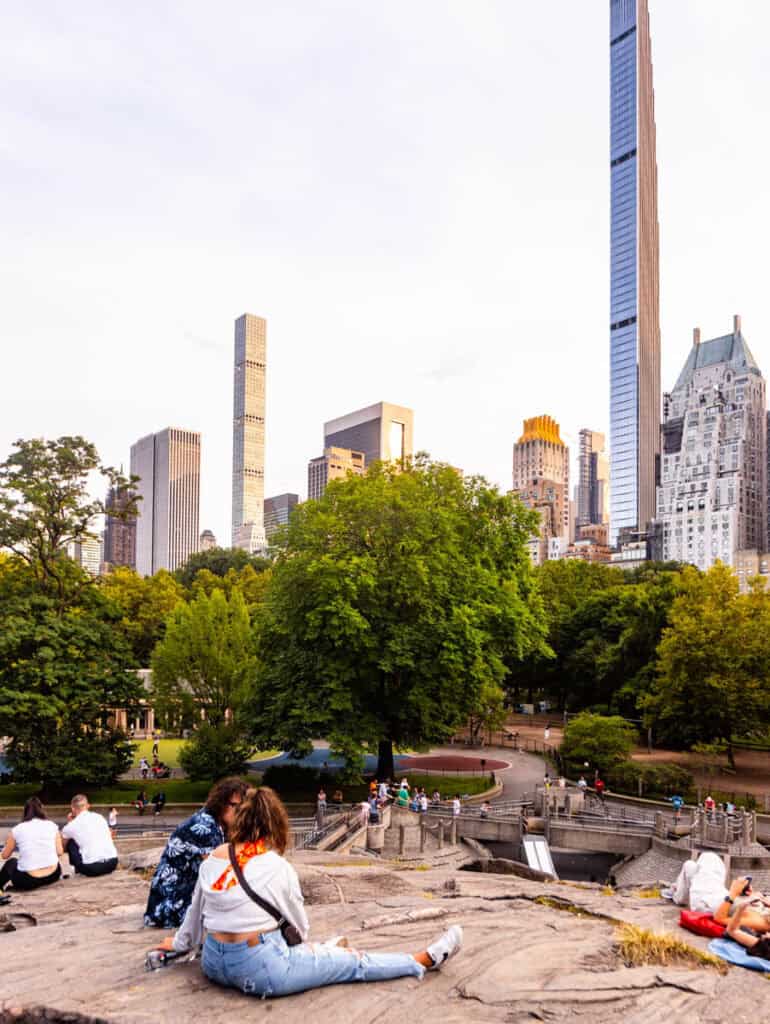 people sitting on big rock in central park looking at the views