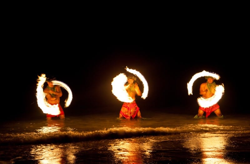 three men on beach throwing flames